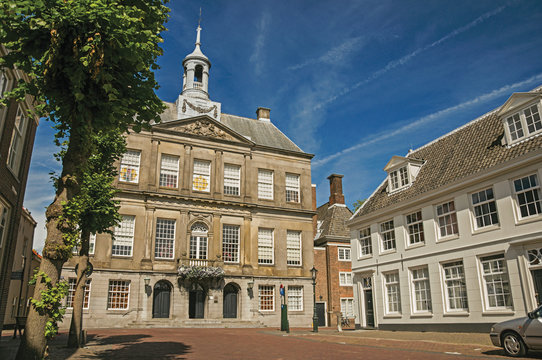 Trees and empty street in front of the City Hall building on sunny day in Weesp. Quiet and pleasant village full of canals and green near Amsterdam. Northern Netherlands.