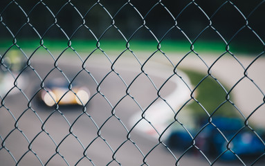 view of blurred racing car from a metal grid - sport background