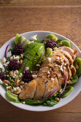 Kiwi, avocado, blackberry, spinach, walnuts salad with chicken and feta cheese. Healthy diet food bowl. vertical
