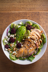Kiwi, avocado, blackberry, spinach, walnuts salad with chicken and feta cheese. Healthy diet food bowl. overhead, vertical