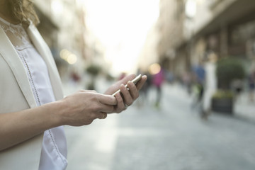 woman looking smartphone in the city, hands detail