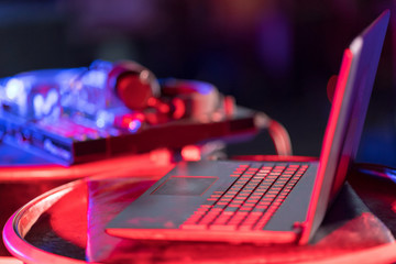 In selective focus of Pro DJ controller.The DJ console cd mp4 deejay mixing desk Ibiza house music party in nightclub with colored disco lights.