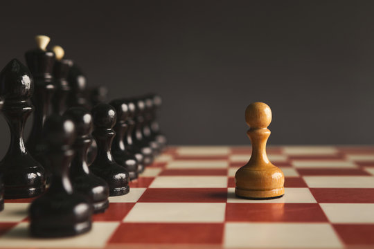 One pawn standing against set of black chess