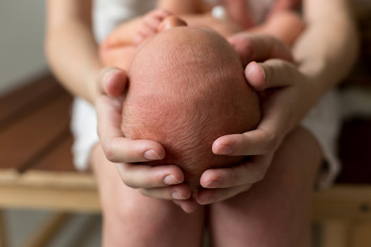 Newborn Baby Is Lying Head In The Hands Of Mother