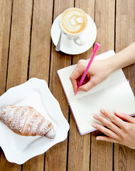 Hands writting at notebook in cafe