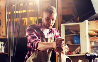 profession, people, carpentry, woodwork and people concept - carpenter working with jointer planing wood plank at workshop