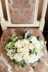 beautiful wedding bouquet with white roses lying on the chair