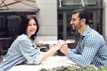 Loving couple holding hands sitting at table in cafe.