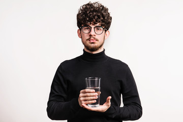 Young man in a studio, holding a glass of water.