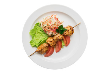 Delicious chicken shish kebab on skewers with vegetables at plate isolated on a white background