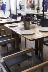 tables decorated with vases on the terrace of an elegant restaurant on the street of a city
