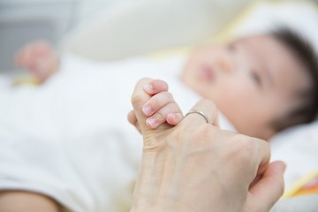 Obraz na płótnie Canvas 母親の指を握る赤ちゃん