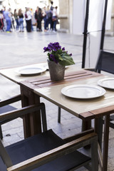 tables decorated with vases on the terrace of an elegant restaurant on the street of a city
