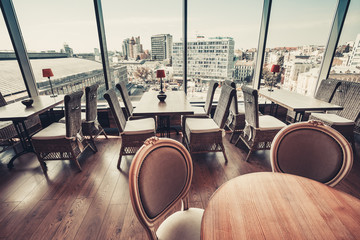 Modern simple cafe interior with wooden furniture and big window city view. Vintage retro instagram Color filter toning