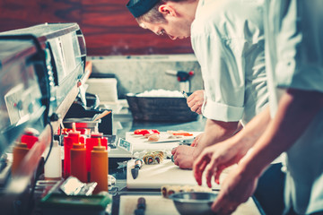 Obraz na płótnie Canvas Two young chefs in white uniform preparing sushi set, only hands close up. Interior of modern restaurant kitchen. Food concept. Vintage instagram Color filter toning