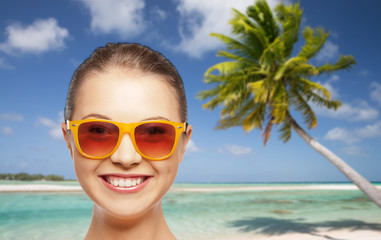 travel, tourism, summer holidays, vacation and people concept - smiling young woman or teenage girl in sunglasses over exotic tropical beach background