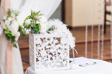 A cute wooden box with a carving for gifts on the table with a white tablecloth on the background...