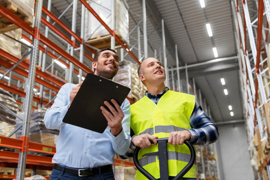 logistic business, shipment and people concept - businessman with clipboard and warehouse worker with loader