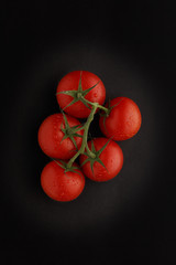 Fresh bunch of vine ripened tomatoes, shot on a dark slate background, with space for copy.