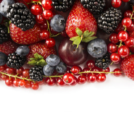 Berries and fruits with copy space for text. Black-blue and red food. Ripe blackberries, blueberries, strawberries, red currants and plums on white background. Top view. 