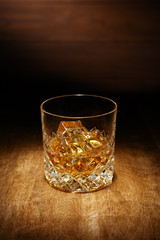 A spotlight on a single crystal glass of scotch whisky, shot on a wooden table top.