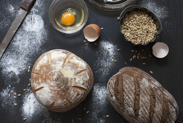 Top view of whole grain breads on black wooden table; culinary concept; selective focus.