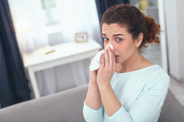 Unknown allergens. Sick lady looking perplexed while frowning her forehead wondering what sort of allergen provoked her allergic reaction