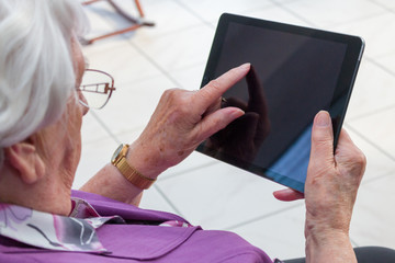 Alte Frau schreibt auf einem Tablet PC