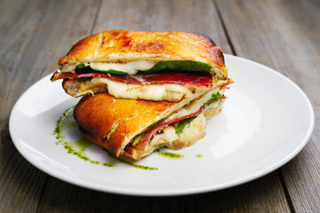 Breakfast baked sandwich with prosciutto, spinach and parmesan cheese in restaurant serving. Food photo, restaurant menu
