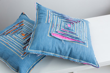 art, modern, decor concept. close up of stylish pillows that are placed on the white table of atelier studio, they are sewed in old technology called patchwork and decorated with simple cuttings