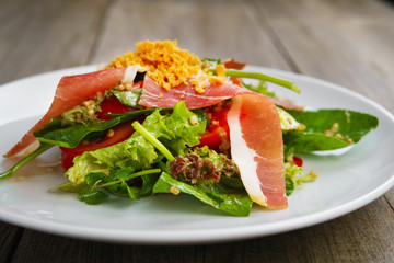 Appetizing gourmet Mediterranean salad of prosciutto and fresh vegetables, banquet, restaurant menu, dining concept