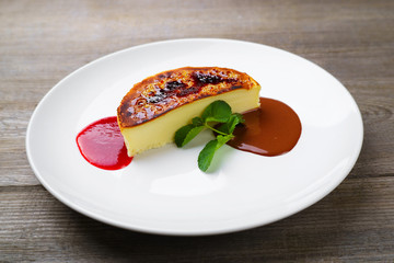 Restaurant menu, food photo, traditional culinary. Cheesecake with strawberry and chocolate sauce on porcelain plate