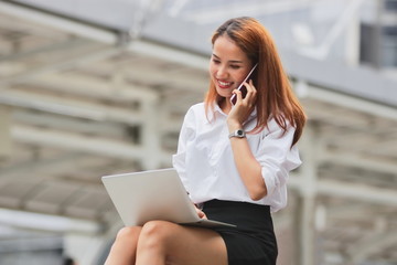 Beauty young Asian business woman using laptop and mobile smart phone for job at outside office.