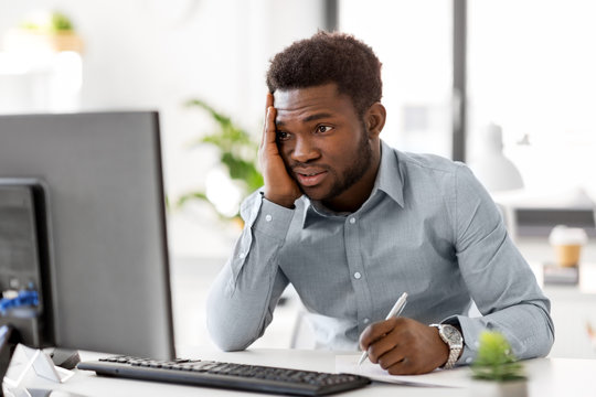 business, people, paperwork and technology concept - stressed african american businessman with computer and papers working at office