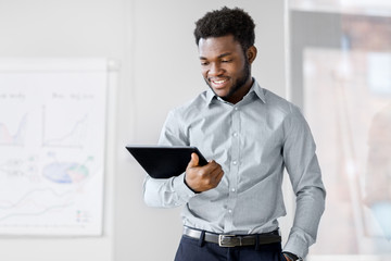 business, people and technology concept - african american businessman with tablet pc computer at...