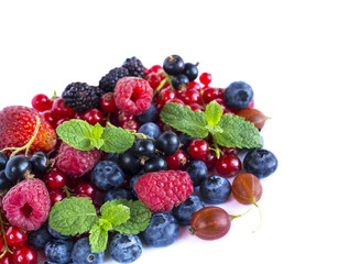 Fruits and berries on white background. Ripe red currants, raspberries, blueberries,  strawberries, gooseberrie, blackberries with a mint leaf. Top view.