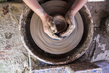 Child hands shaping bowl on potters wheel