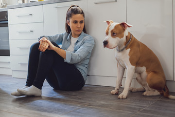 Woman sitting on the kitchen floor mad on her dog