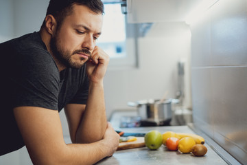 Angry man leaning on a kitchen countertop