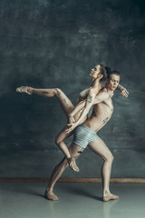 The young modern ballet dancers posing on gray studio background