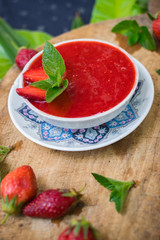 Fresh raw strawberry mint dessert for breakfast. Fruit yoghurt or smoothie on wooden board. Fruit jam mixed with blender. Raw vegan vegetarian healthy food