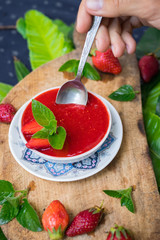 Woman hands holds fresh raw strawberry mint dessert for breakfast. Fruit yoghurt or smoothie on wooden board. Fruit jam mixed with blender. Raw vegan vegetarian healthy food