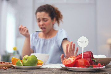 No vegetables. Young woman looking unhappy acting conscious while refusing to consume vegetables which provoke her allergic response