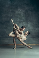 Fototapeta na wymiar The young modern ballet dancers posing on gray studio background