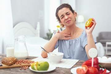Citrus allergy. Young beautiful woman looking sore and getting an allergic rash while eating an orange during her dinner