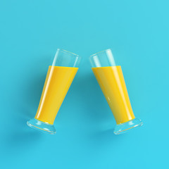 Two glasses with yellow cocktails on bright blue background in pastel colors. Minimalism concept