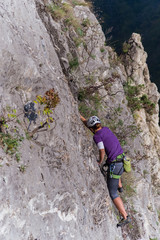 Young woman lead climbing on cliff