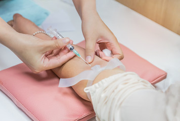 Nurse injecting with syringe to patient's arm drawing blood sample for blood test in hospital