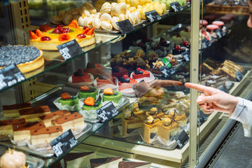 woman choose sweets in store. deserts shop