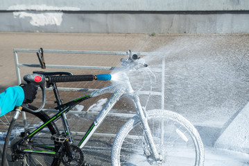 young sport woman washing bicycle at self-service car wash